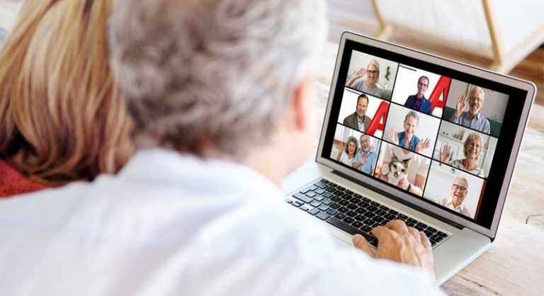Zwei Frauen schauen auf einen Laptop, auf dessen Bildschirm 9 einzelne Fenster von Teilnehmern eines Online-Kurses zu sehen sind.